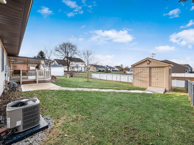 view of yard featuring a fenced backyard, a residential view, an outdoor structure, a shed, and central AC