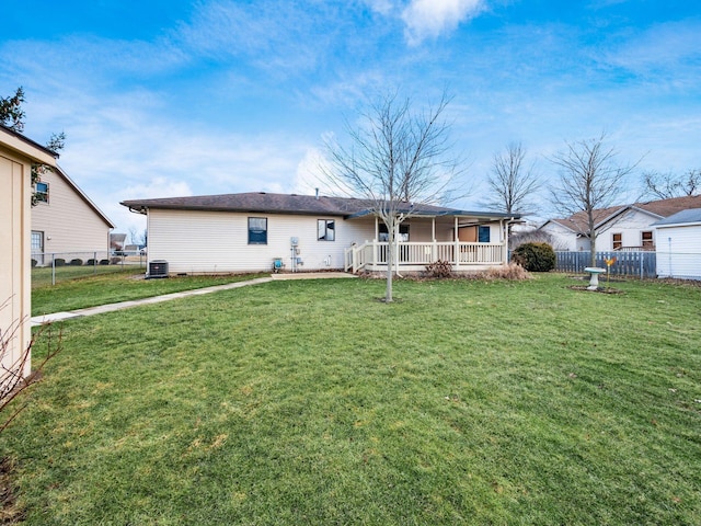 rear view of house with central AC, a yard, and fence