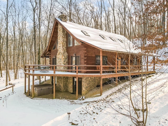 view of front of home featuring stone siding, a chimney, log siding, and a deck