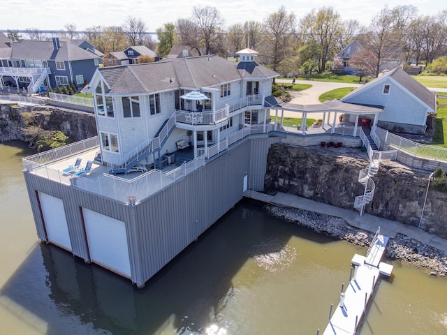 view of dock with stairs, a water view, and a residential view