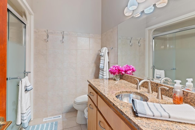 bathroom with tile patterned flooring, visible vents, toilet, an enclosed shower, and tile walls