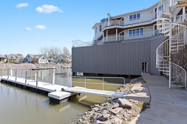 view of dock with stairs, a water view, and a residential view