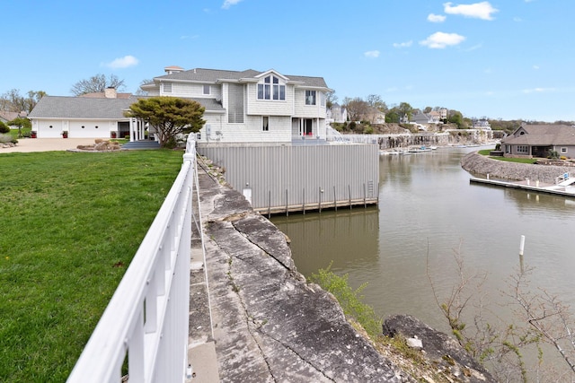 view of dock featuring a residential view, fence private yard, a yard, and a water view