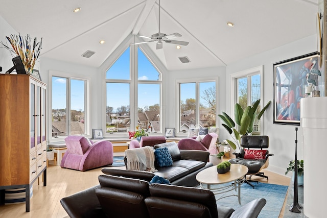 living room with a wealth of natural light, light wood-type flooring, high vaulted ceiling, and recessed lighting