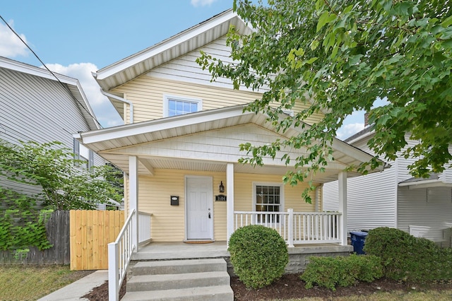 view of front of home featuring covered porch and fence