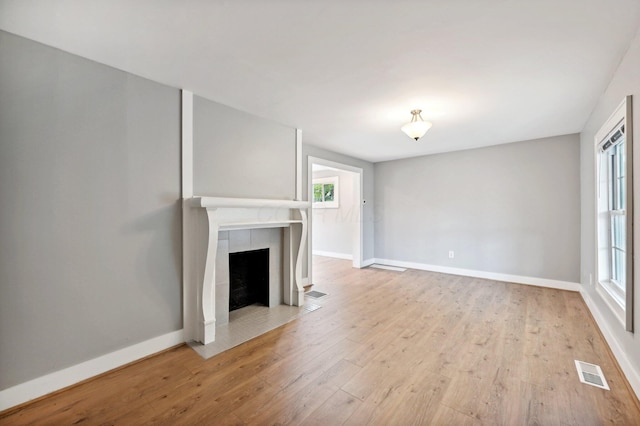 unfurnished living room featuring light wood-style floors, baseboards, a fireplace, and visible vents