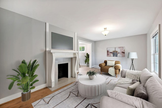 living area with light wood-style floors, baseboards, and a tiled fireplace