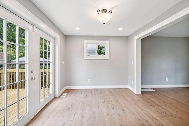 empty room featuring light wood-style floors, french doors, and baseboards