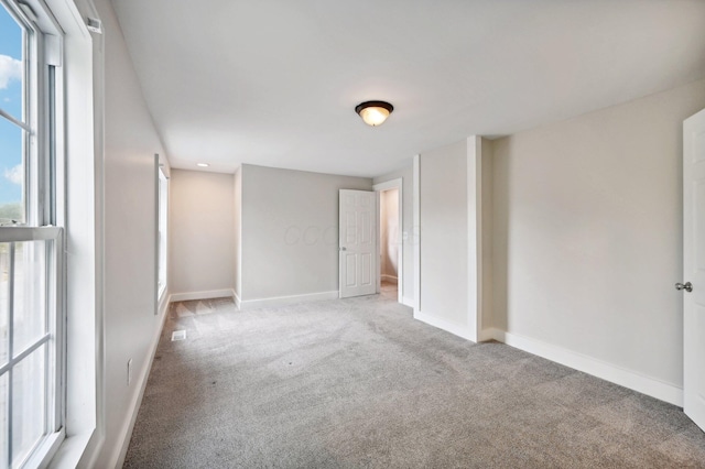 empty room featuring light carpet and baseboards