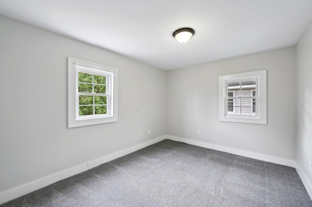 empty room with dark carpet and baseboards