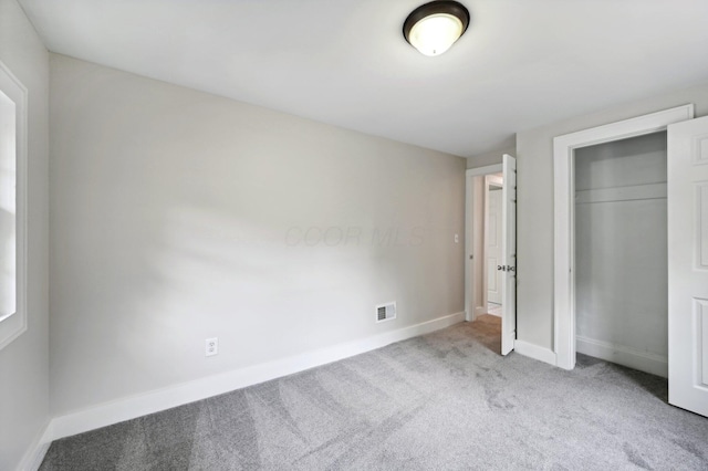 unfurnished bedroom featuring a closet, carpet, visible vents, and baseboards