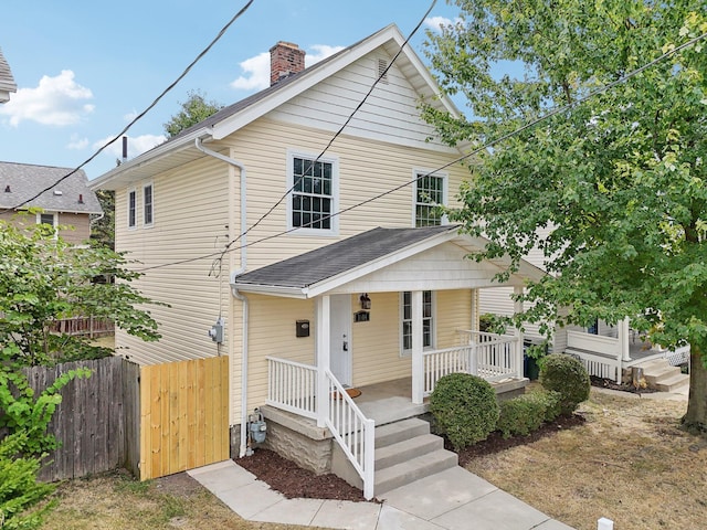 view of front of property featuring a porch, a chimney, and fence