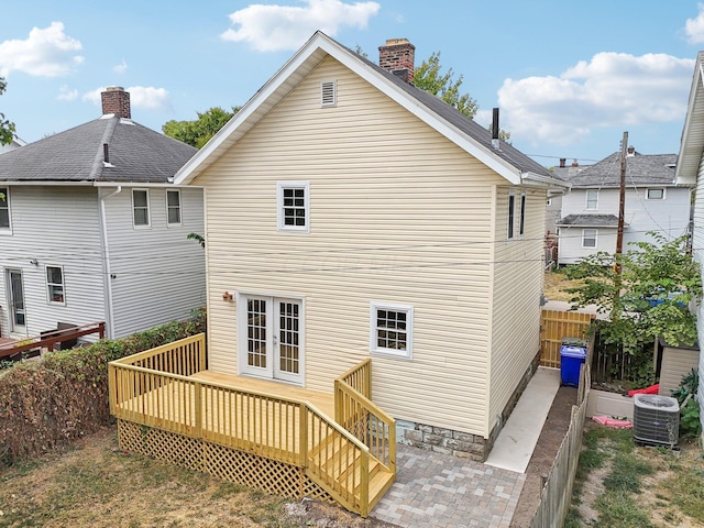 back of property with french doors, a chimney, fence, a wooden deck, and central AC