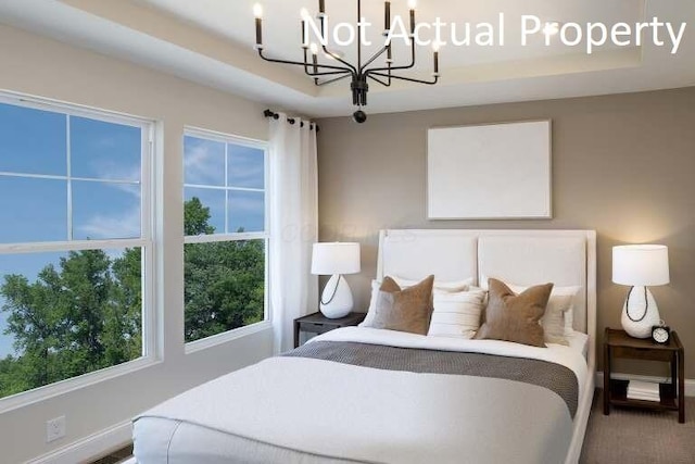 bedroom featuring an inviting chandelier, baseboards, and a tray ceiling