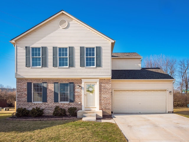 colonial home featuring a front yard, an attached garage, brick siding, and driveway