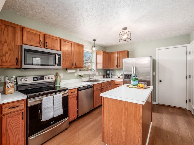 kitchen with light countertops, light wood-type flooring, appliances with stainless steel finishes, and a sink