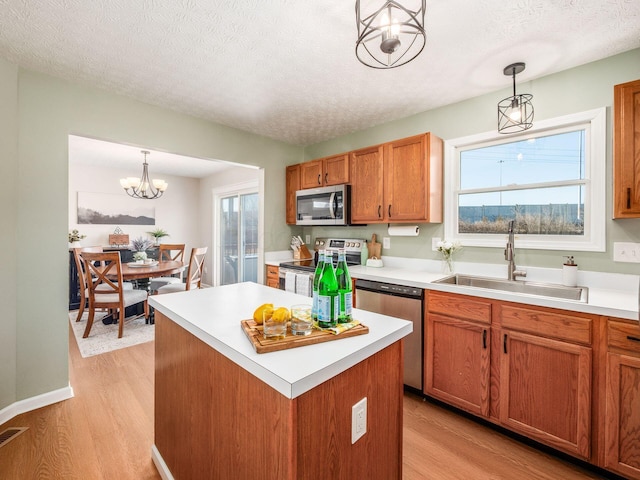 kitchen with light wood finished floors, stainless steel appliances, light countertops, and a sink