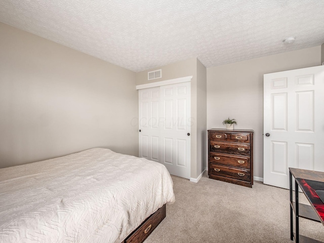 bedroom with visible vents, baseboards, light colored carpet, a closet, and a textured ceiling