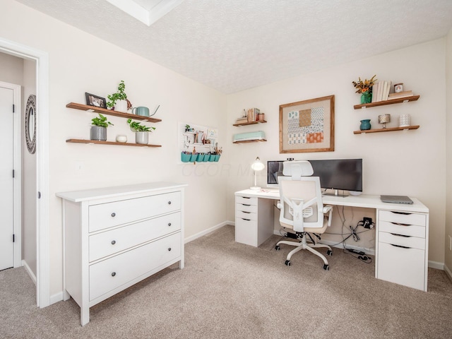 home office featuring light colored carpet, baseboards, and a textured ceiling