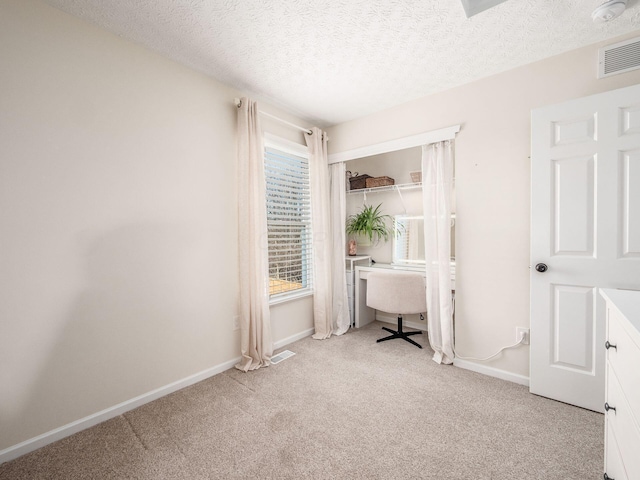 unfurnished bedroom with a closet, visible vents, a textured ceiling, and carpet floors