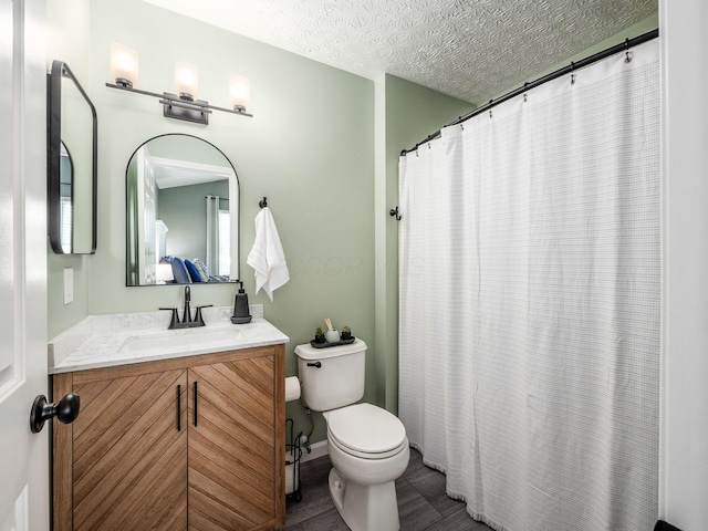 bathroom featuring baseboards, toilet, a shower with shower curtain, vanity, and a textured ceiling