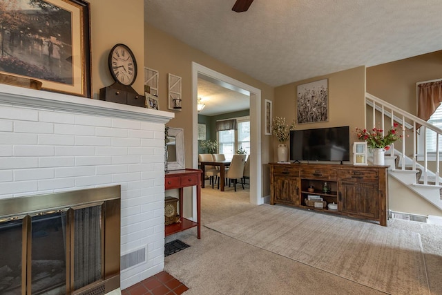 living room with visible vents, stairs, a textured ceiling, carpet flooring, and a fireplace