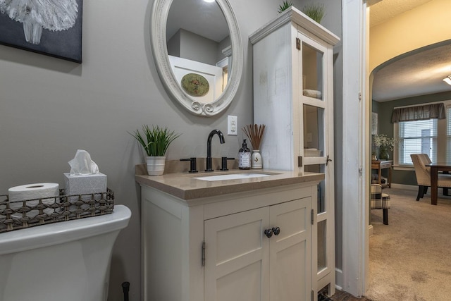 half bathroom with toilet, baseboards, and vanity