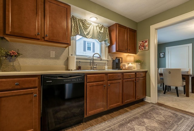 kitchen featuring a sink, decorative backsplash, dishwasher, and light countertops