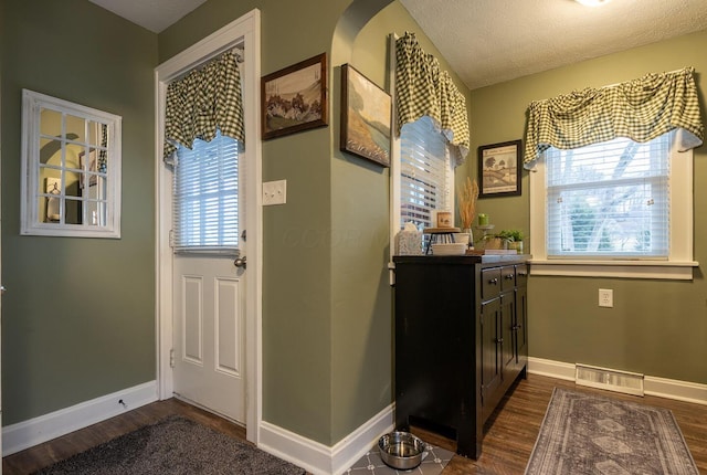 interior space featuring dark wood-type flooring, visible vents, a textured ceiling, and baseboards