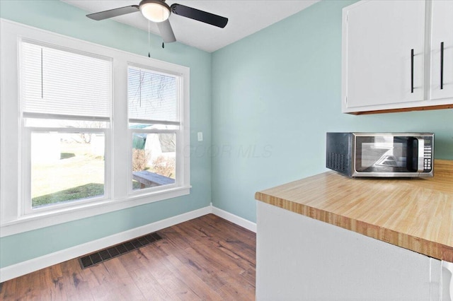 kitchen with dark wood-type flooring, light countertops, visible vents, and baseboards