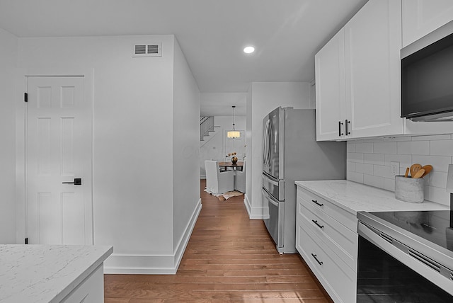 kitchen featuring visible vents, white cabinets, light stone counters, wood finished floors, and stainless steel appliances