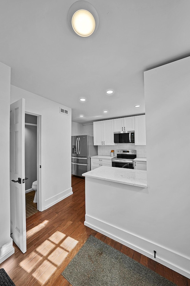 kitchen with dark wood-style floors, visible vents, decorative backsplash, appliances with stainless steel finishes, and white cabinets