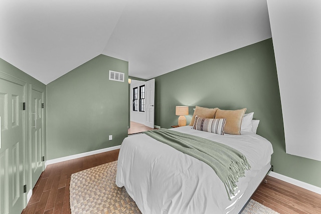 bedroom featuring visible vents, vaulted ceiling, baseboards, and wood finished floors