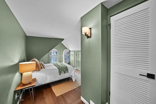 bedroom featuring lofted ceiling, baseboards, and wood finished floors