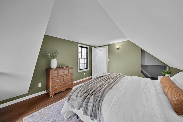 bedroom with baseboards, vaulted ceiling, and wood finished floors