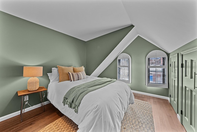 bedroom with lofted ceiling, baseboards, and wood finished floors