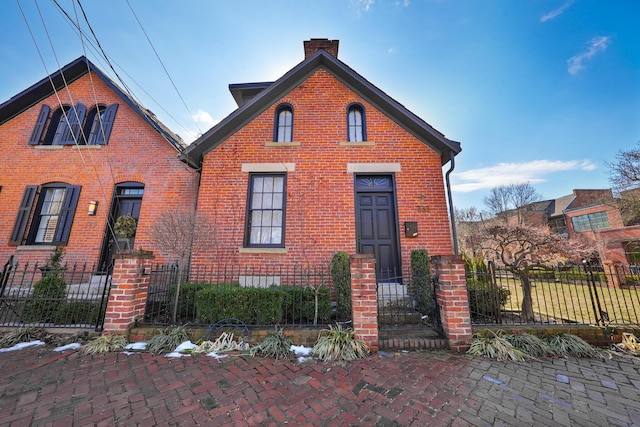 view of front of home featuring a fenced front yard, a chimney, and brick siding