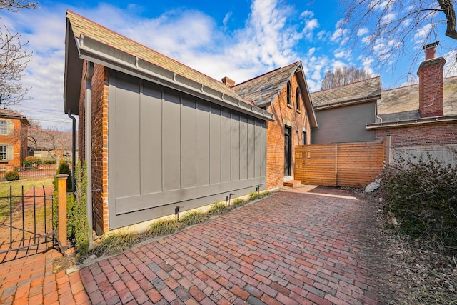 view of home's exterior featuring a patio area, fence, board and batten siding, and brick siding