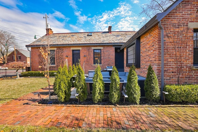 view of front of house with a high end roof, fence, a front lawn, and brick siding