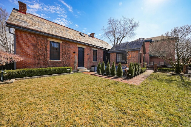 view of front of property featuring a high end roof, brick siding, a chimney, and a front lawn