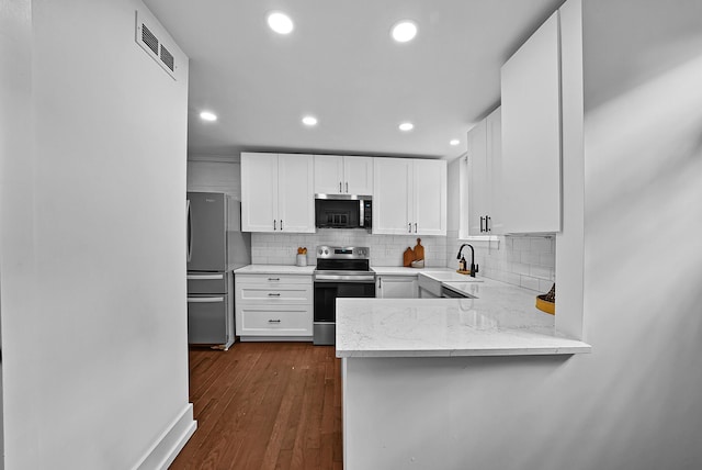 kitchen with visible vents, white cabinets, appliances with stainless steel finishes, a sink, and backsplash