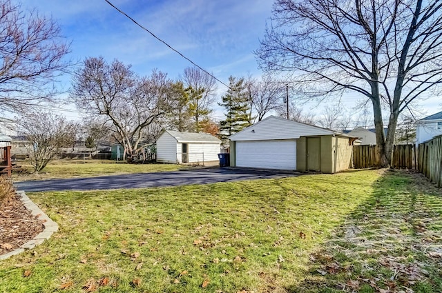 view of yard featuring a garage, an outdoor structure, and fence