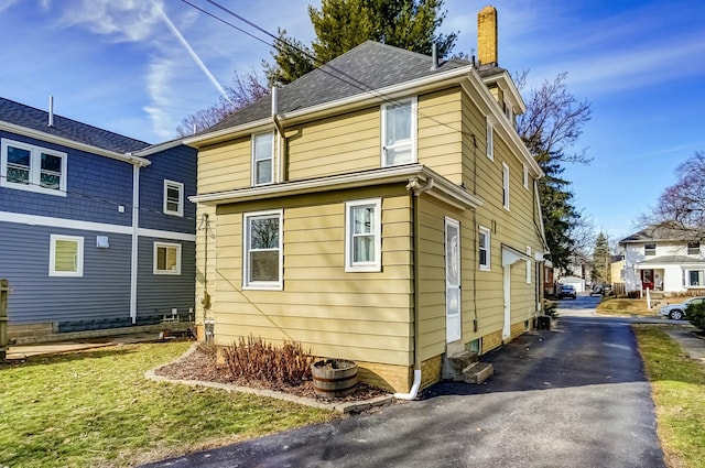 exterior space featuring roof with shingles and a chimney