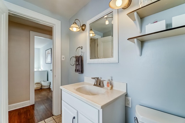 half bath featuring toilet, wood finished floors, and vanity