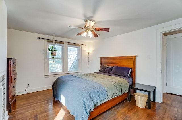 bedroom with ceiling fan, wood finished floors, and baseboards