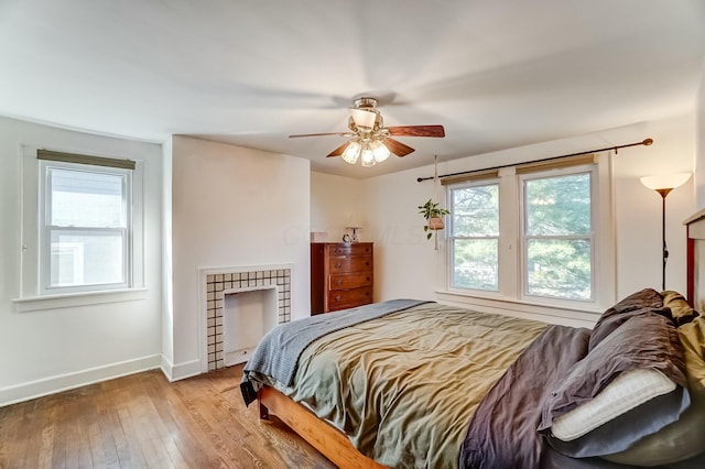 bedroom with ceiling fan, hardwood / wood-style floors, multiple windows, and baseboards