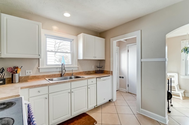 kitchen with arched walkways, white appliances, light tile patterned flooring, and a sink