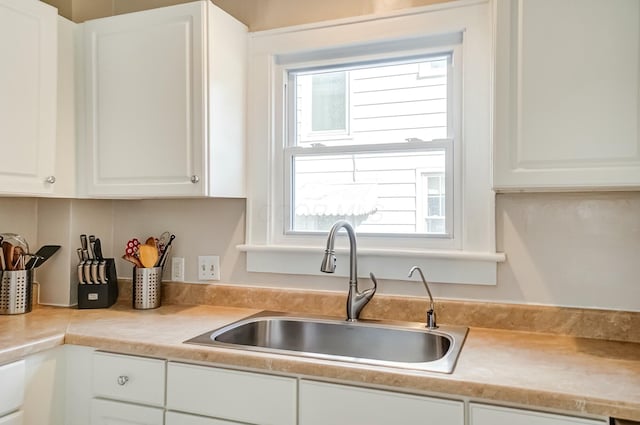 kitchen featuring a wealth of natural light, white cabinetry, light countertops, and a sink