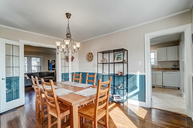 dining room with a notable chandelier, crown molding, and wood finished floors