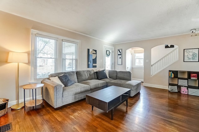 living room featuring dark wood-style floors, baseboards, stairs, and visible vents